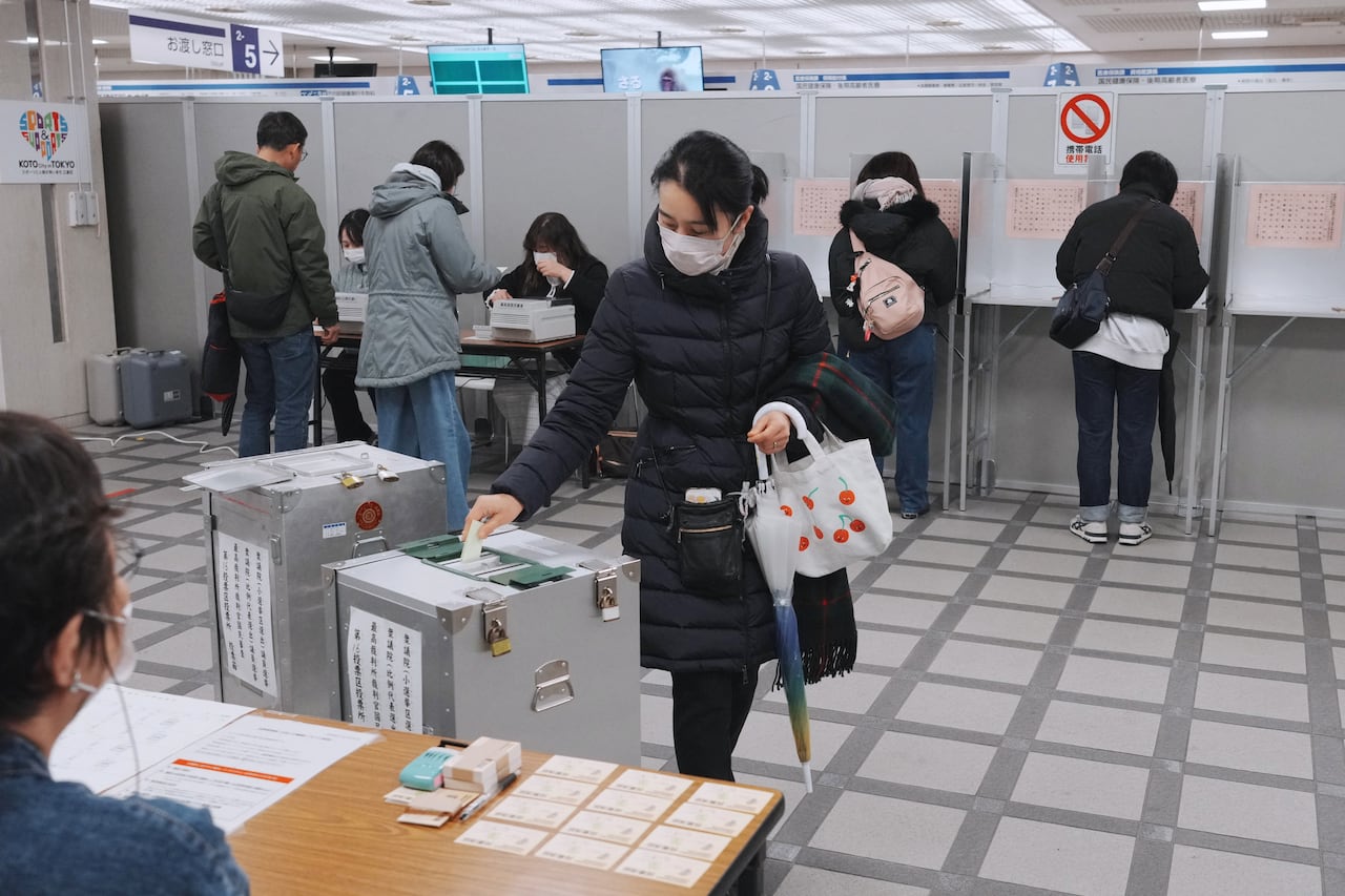 A voter casts a ballot into a box.