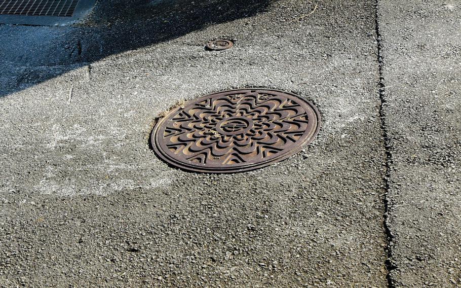 A close-up view of a manhole cover on a residential street.