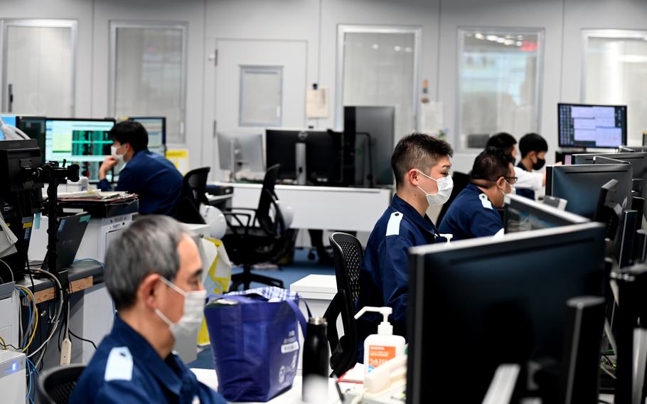 Japan coast guard personnel sit at computer stations in a large office.