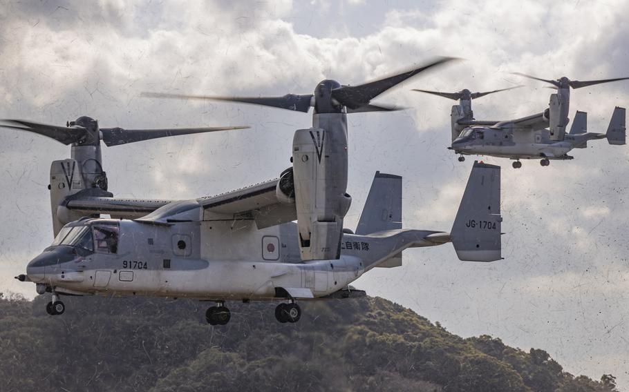A pair of V-22 Ospreys hover while preparing to land.
