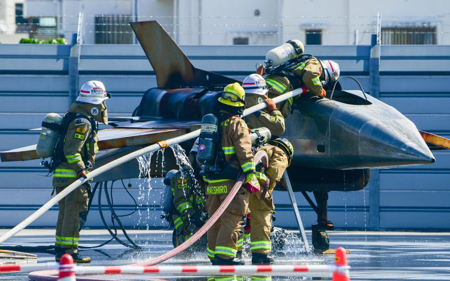 Firefighters use hoses to spray a mock aircraft during an emergency drill.