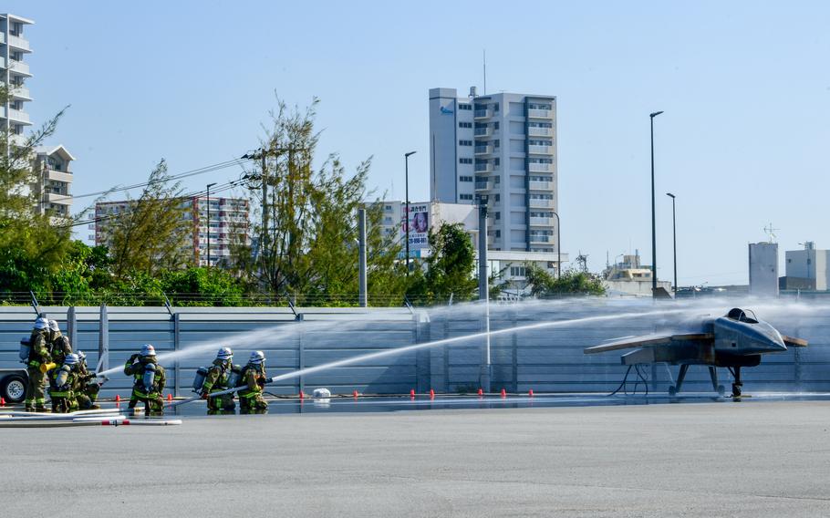 Firefighters work together to put out flames on a mock aircraft.