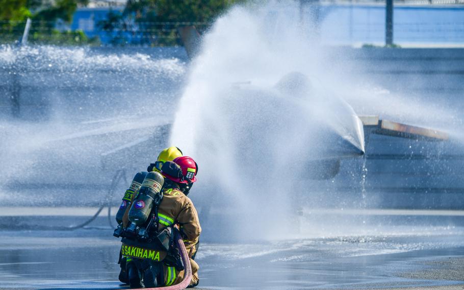 Firefighters spray water to put out flames on a mock aircraft.