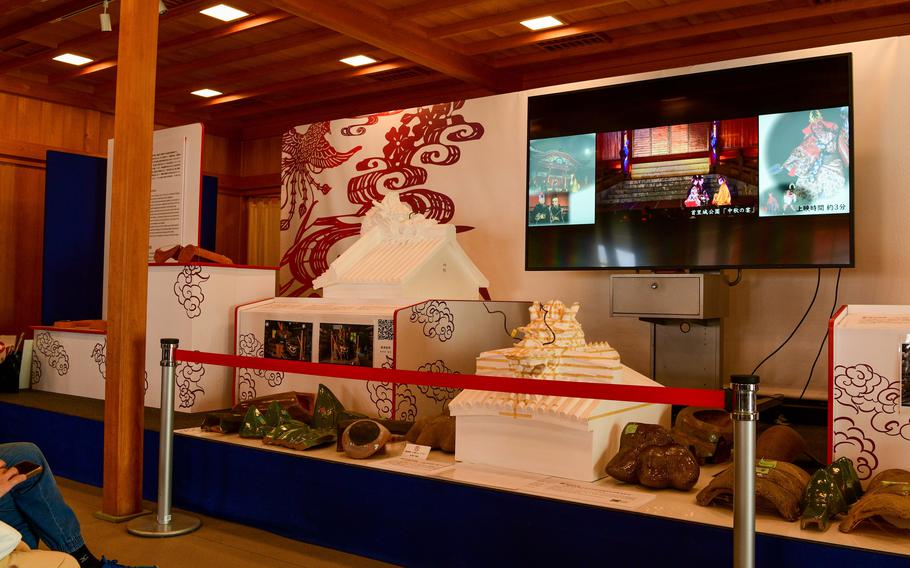 A roped-off display contains clay objects and textiles.