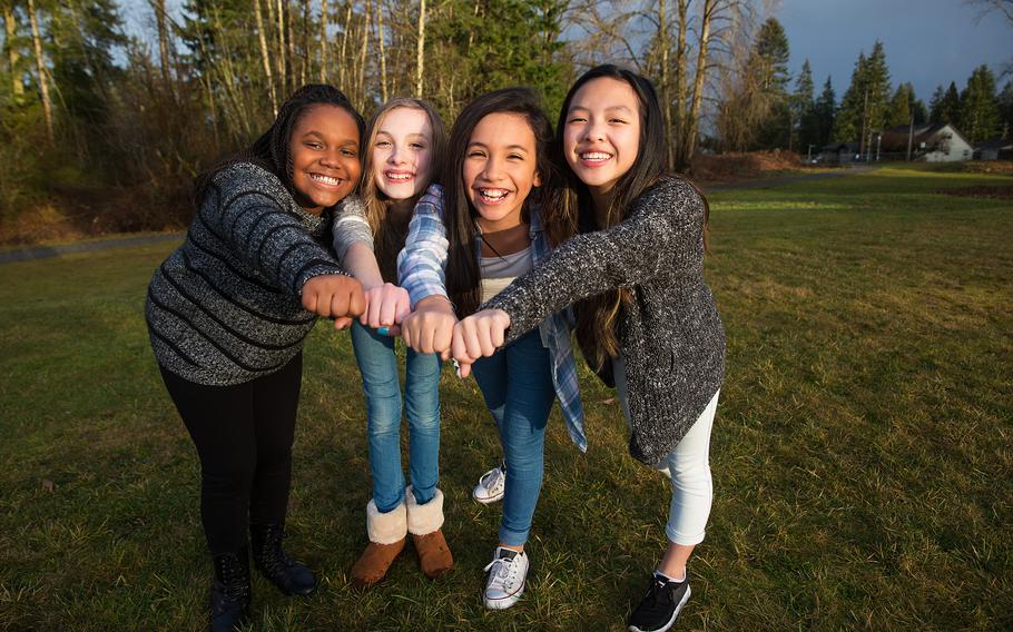 Four girls pose for a photo in the grass.