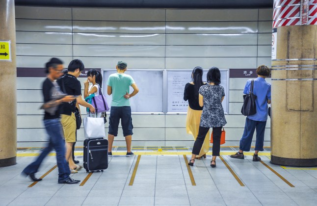 People waiting for train standing on yellow line at subway station