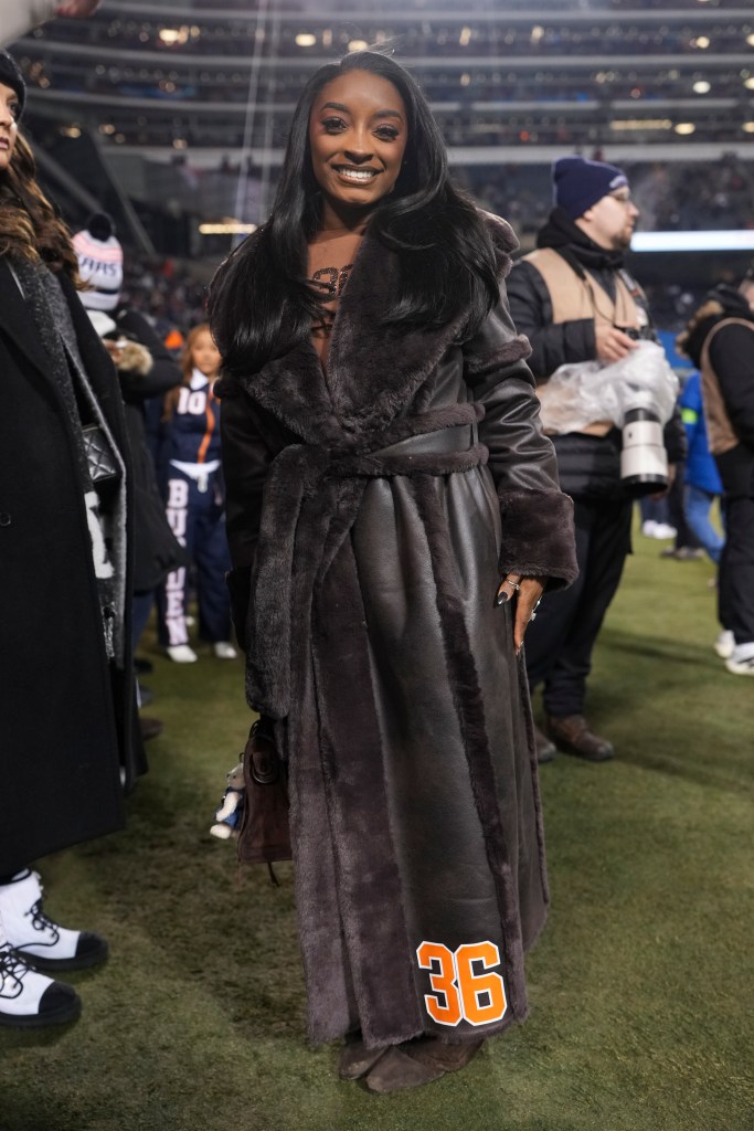Simone Biles stands on the field before a game