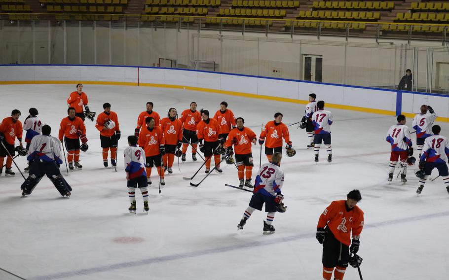 There are many hockey players on the ice rink.