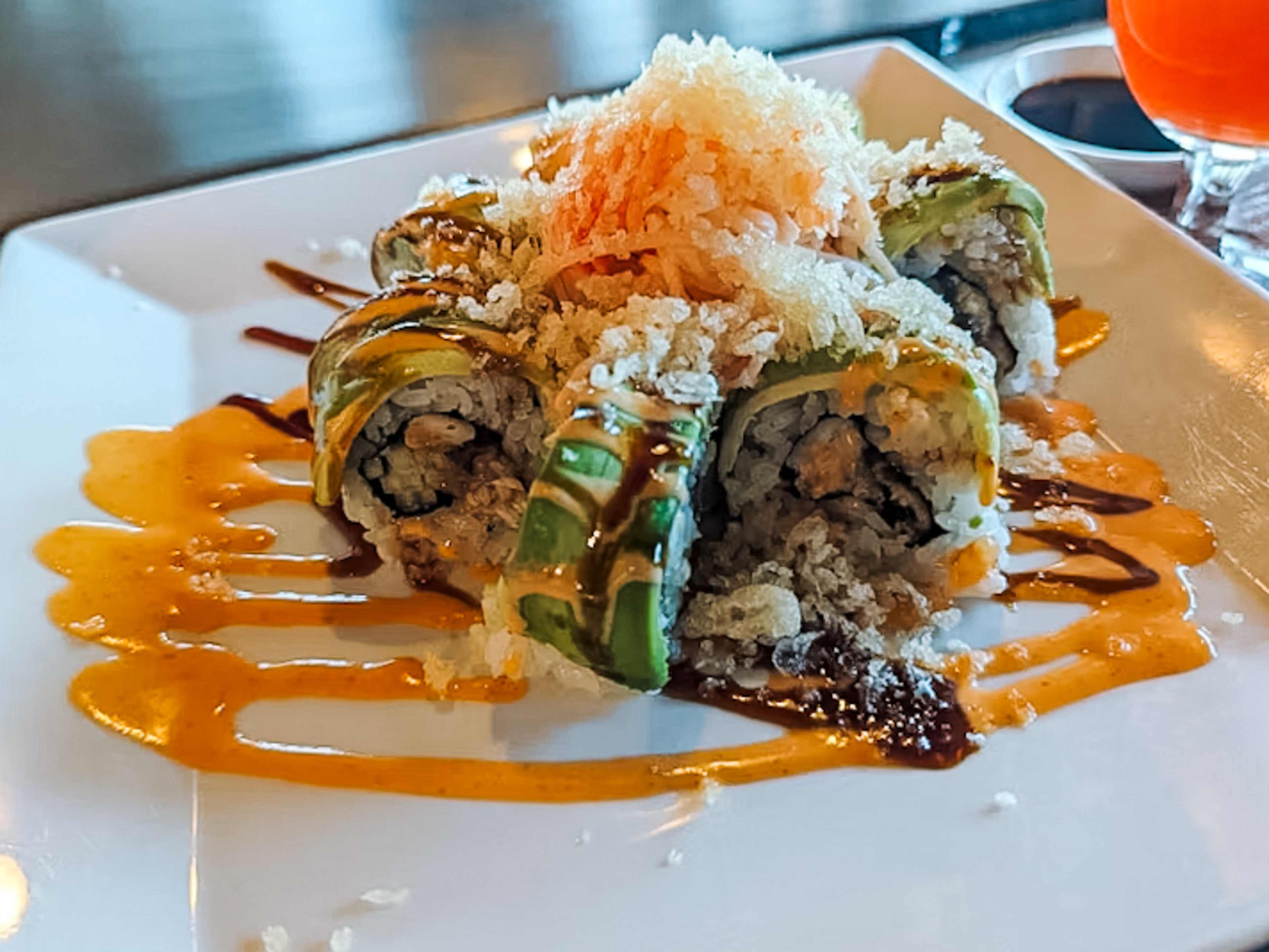 sushi roll arranged on a plate and covered with sauces