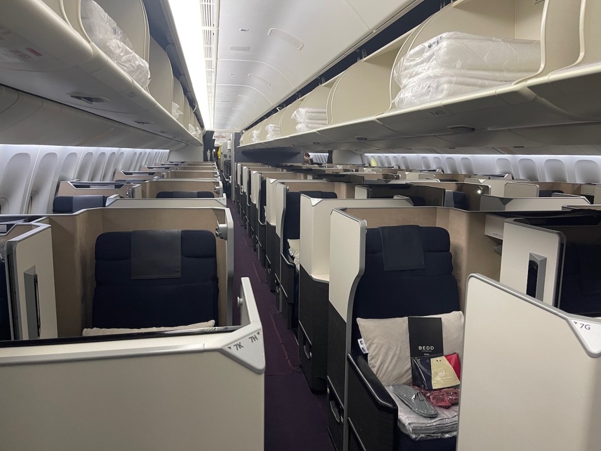 An interior view of the Japan Airlines business class cabin, showing rows of private seating pods with high partitions.