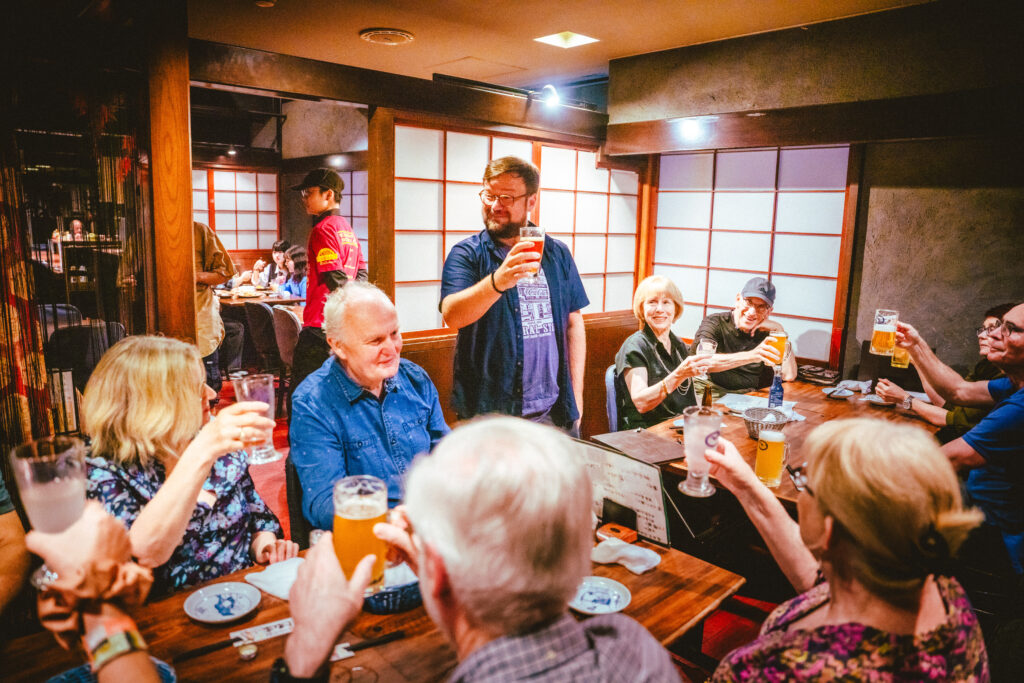 An Inside Japan tour leader and clients make a toast during a meal.