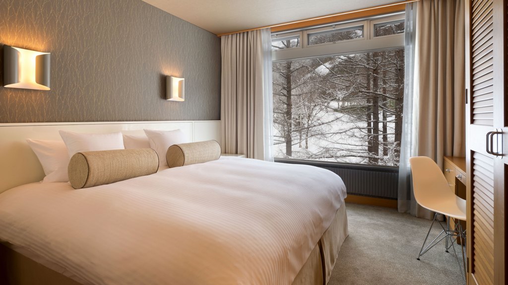 a bedroom with bed, desk, wardrobe, and large window