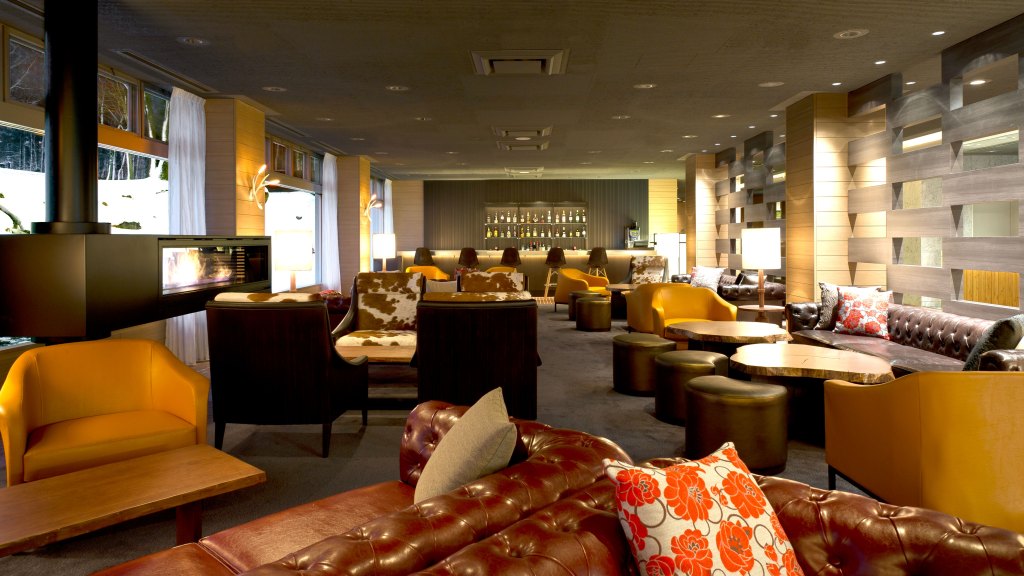 a lounge with various seating options, fireplace, and bar in background