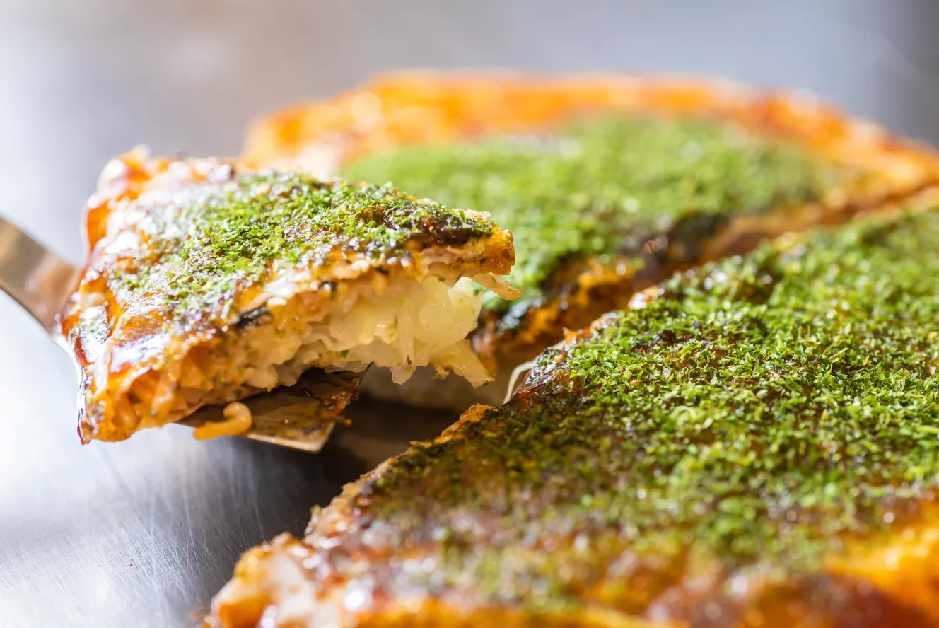 Okonomiyaki being served on a spatula.
