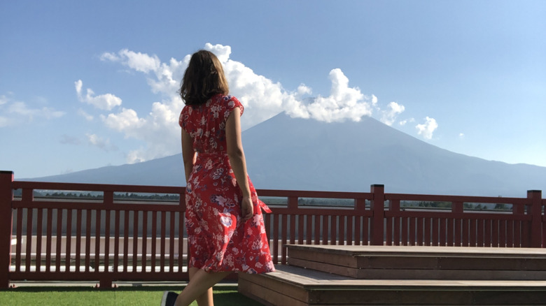 A young woman poses in front of Mt. Fuji at an observation deck at Fuji Station, Shizuoka, Japan