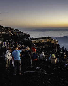 Climbers gather to watch the sunrise at the summit.