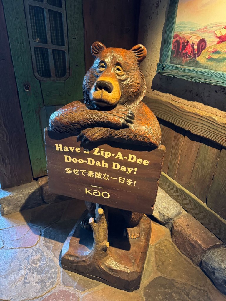 bear holding sign which says zip a dee doo dah
