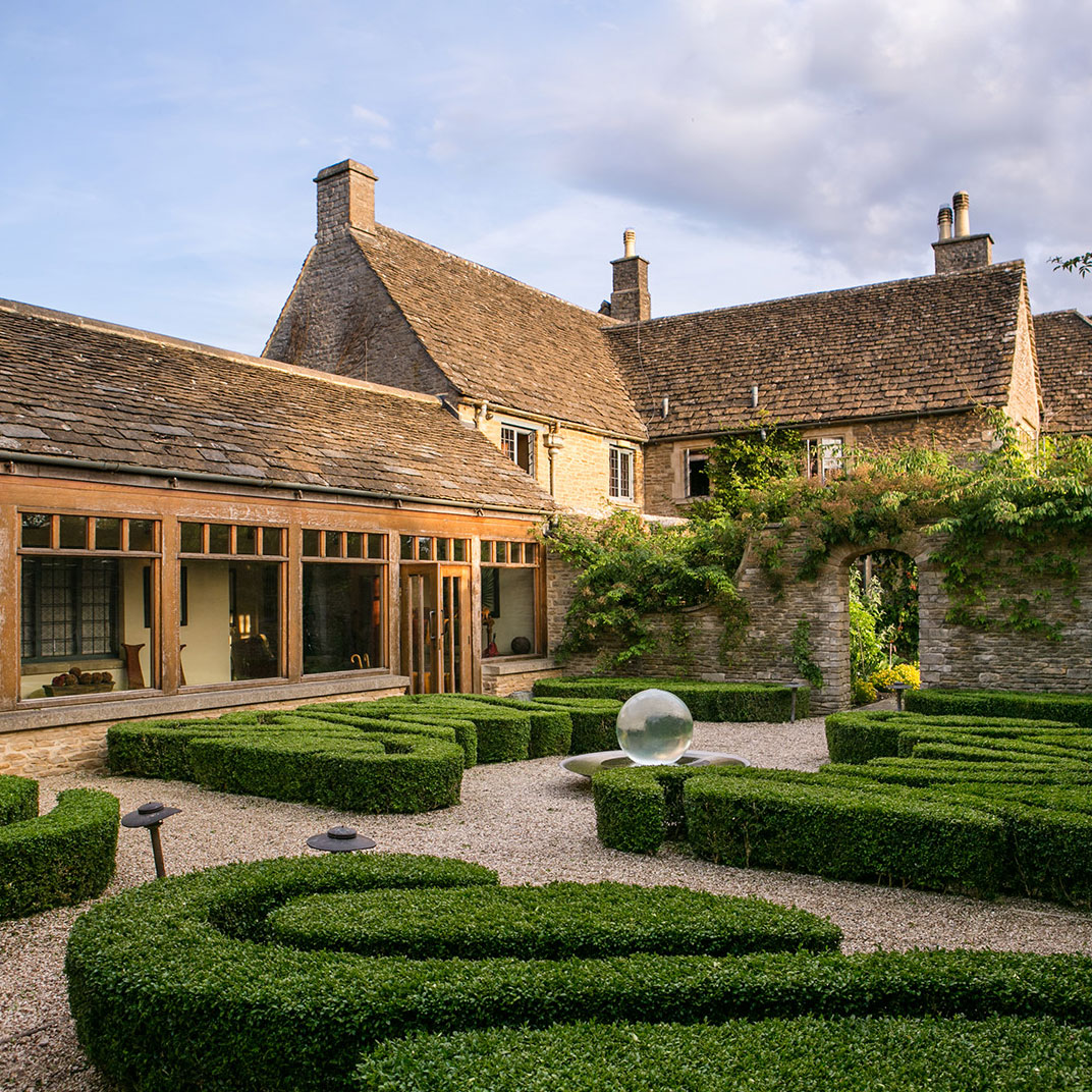 Honey‑colored stone, mullioned windows and clustered roofs give Whatley Manor a classic Cotswold air. © Whatley Manor