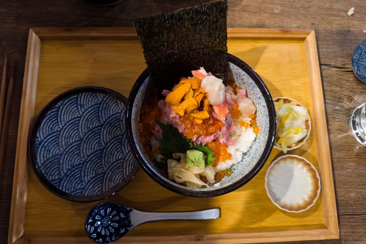 Overhead view of a rice bowl topped abundantly with assorted raw seafood.