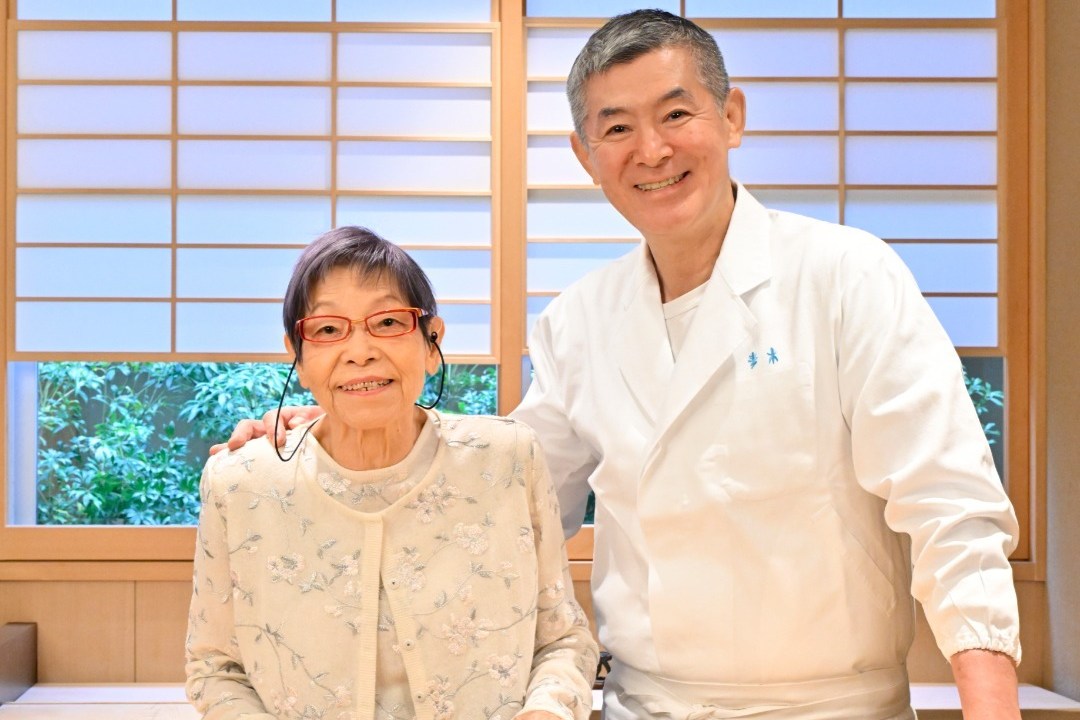 Shopkeeper Toshikatsu Aoki and Lady boss Toyoko Aoki smiling behind a counter.