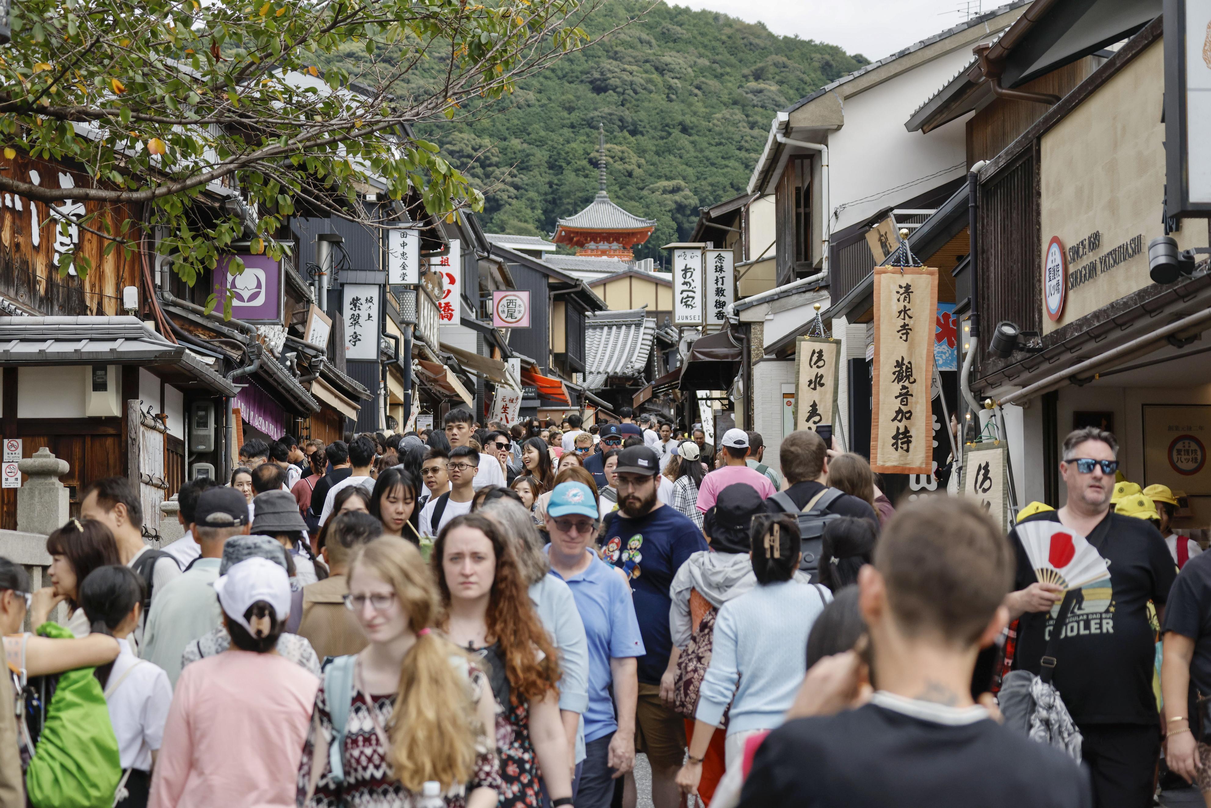 Foreign tourists walking through Kiyomizuzaka near Kiyomizu temple in Kyoto, Japan.