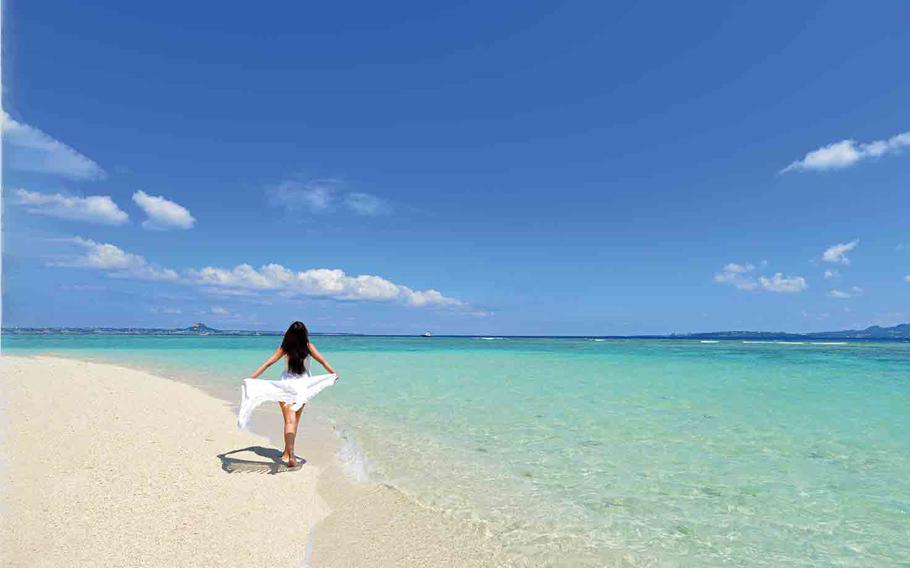 A woman on the beach spreading a white cloth.