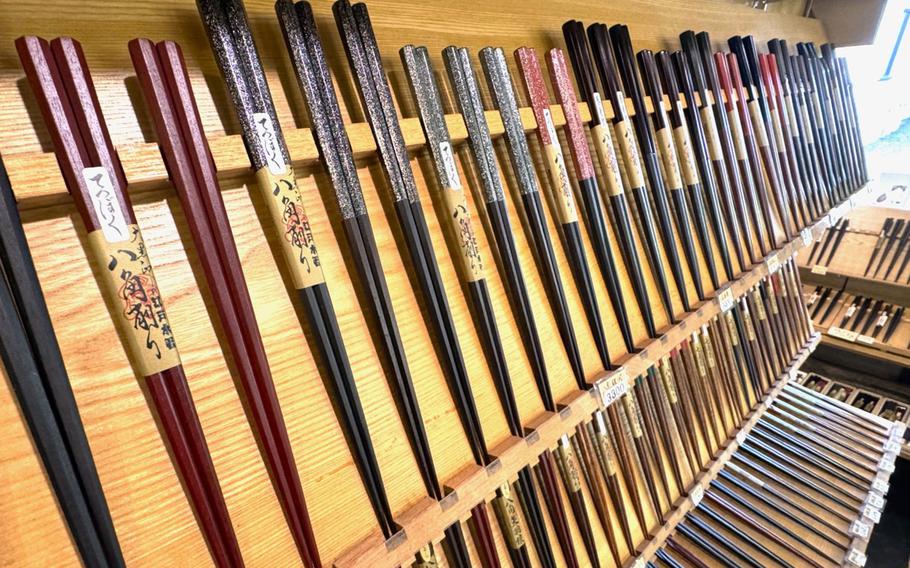 Rows of shiny chopsticks are displayed in a shop.