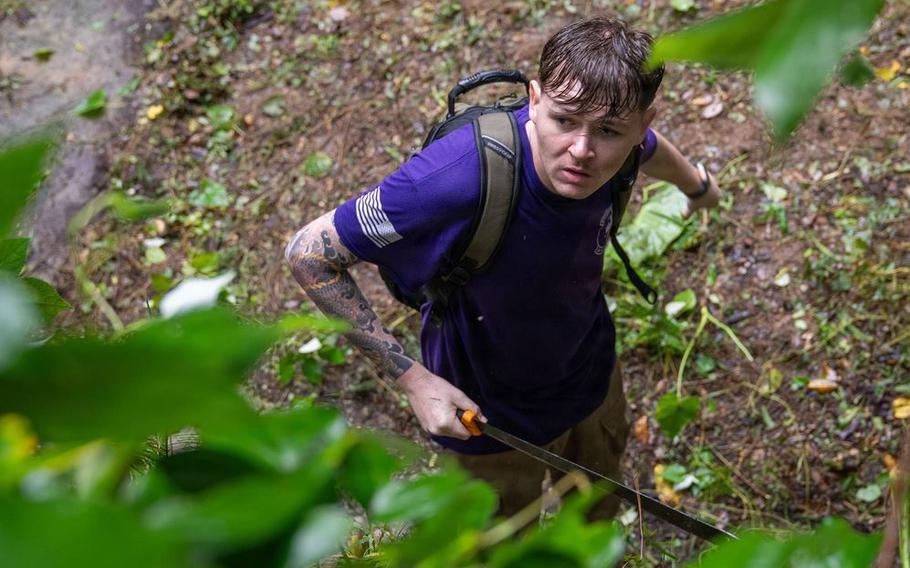 U.S. Air Force Airman 1st Class Gavyn French, 18th Munitions Squadron munitions support equipment maintenance crew chief, cuts vines surrounding an ancestral tomb in preparation for Shimi at Kadena Air Base.
