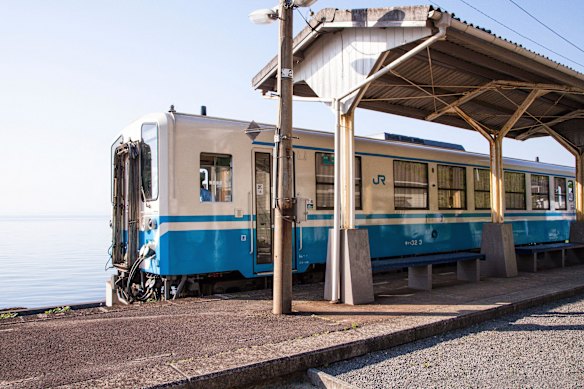 Against the scenic backdrop of the Seto Inland Sea, a Japan Rail train pauses at Shimonada station.