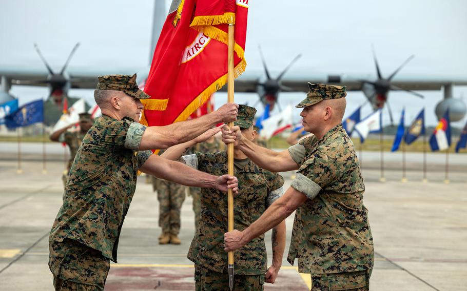 Marcus Annibale passes a 1st Marine Aircraft Wing flag to Simon Doran.