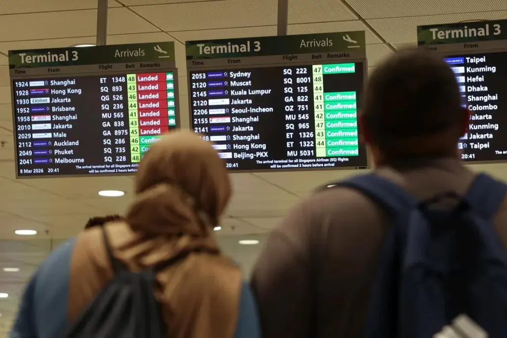 Visitors looking at the flight information display board at the arrival hall of Changi Airport Terminal 3 at 8.45pm on March 8, 2026. ST PHOTO: BRIAN TEO