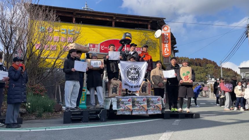 Miura and his team celebrate their victory on the podium, taking home 90 kilograms of rice as their first-place prize.