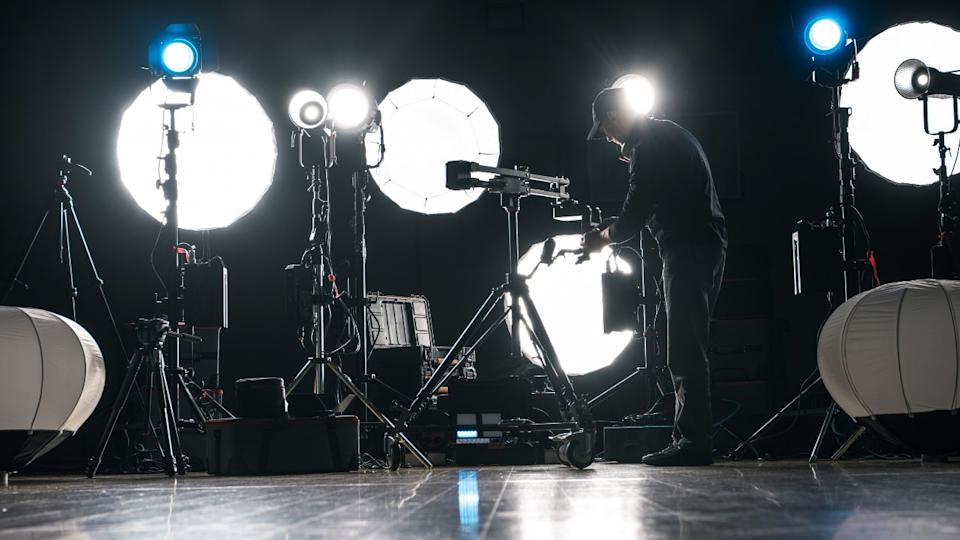 A Man Assembling Powerful Modern LED Video and Photo Lighting Inside Dark Production Studio
