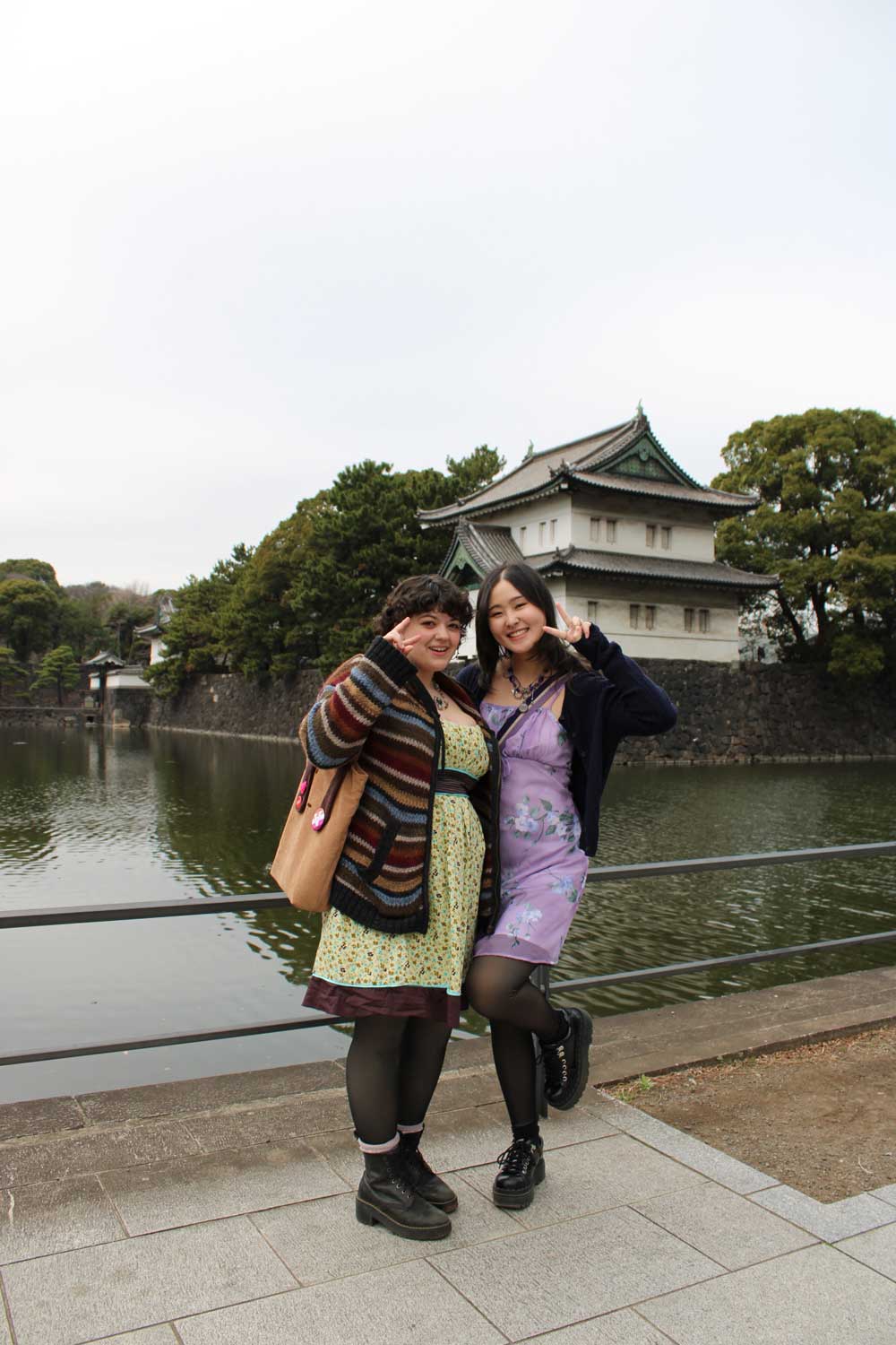 Two friends posing by a moat with a traditional Japanese castle behind them.