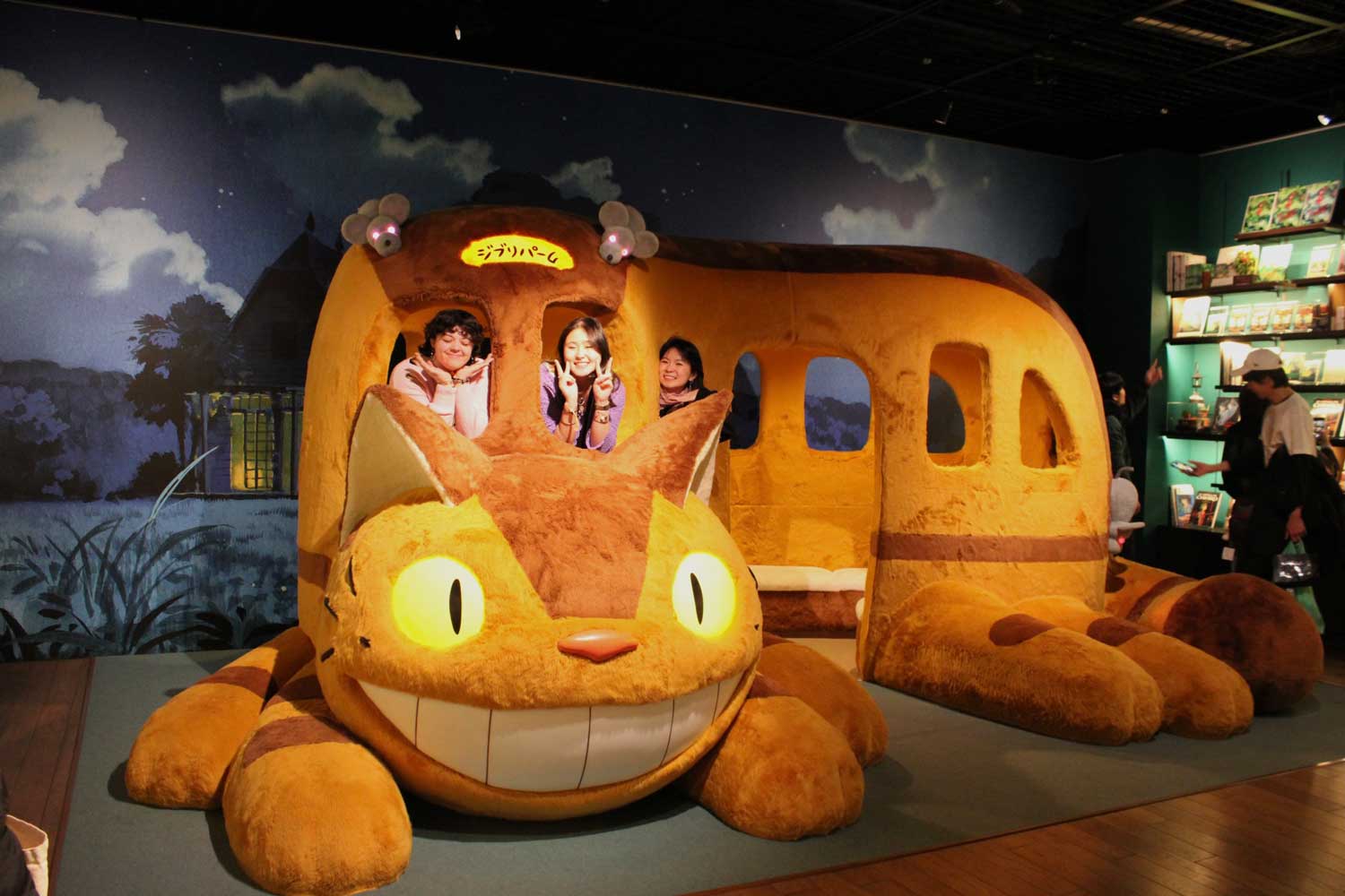 People posing inside a large Catbus from My Neighbor Totoro exhibit.