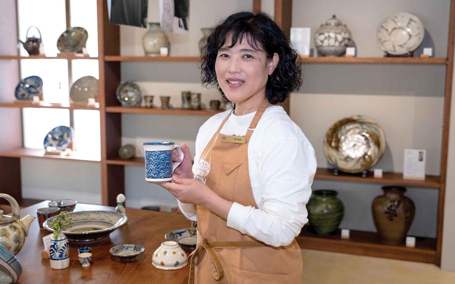 A staff member at Yomitan Garden holds a pottery.