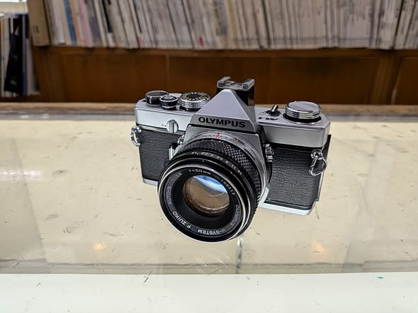 a silver an black slr sits on a marked up glass display case