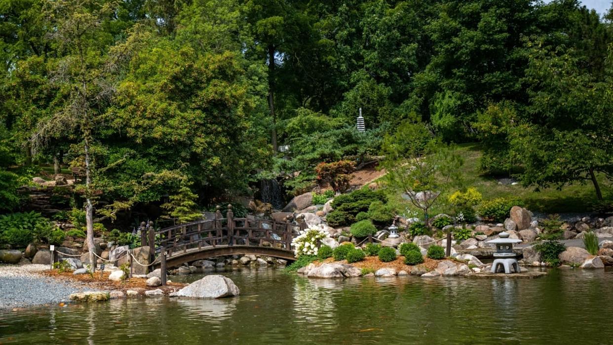 A view of the wooden bridge and lake at Anderson Japanese Gardens on a sunny day, Rockford, Illinois, United States