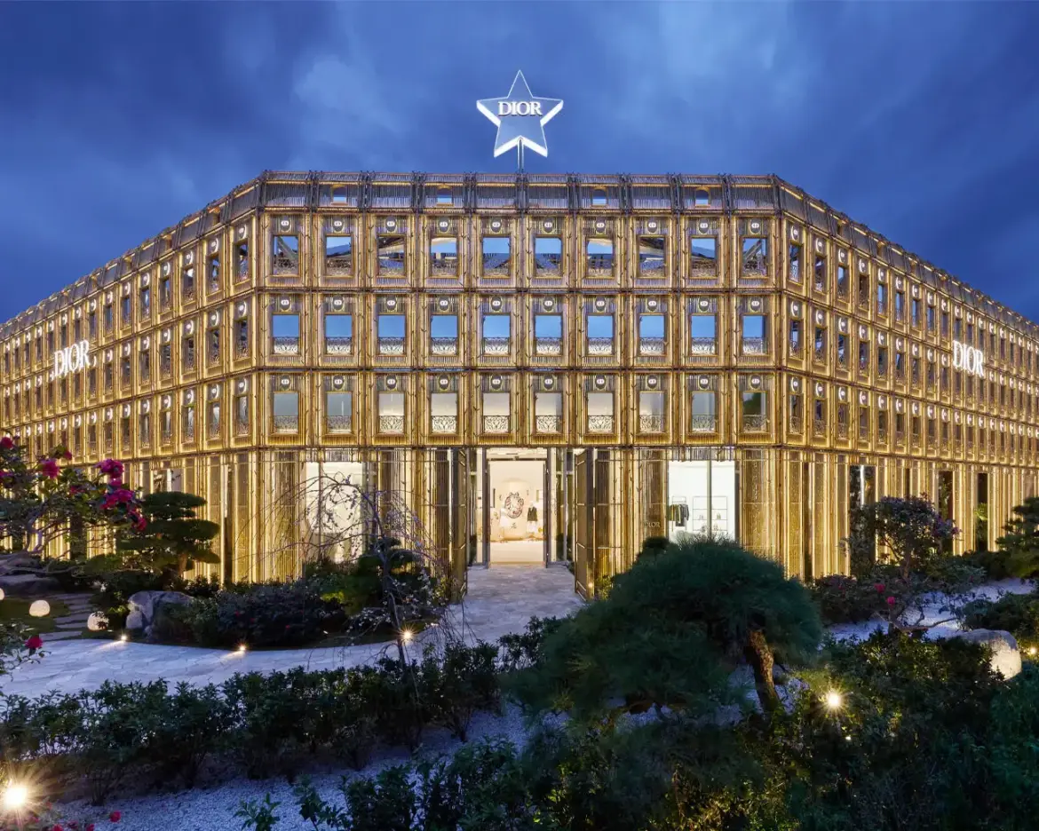 Dior Bamboo Pavilion in Tokyo illuminated at night with golden facade and garden setting