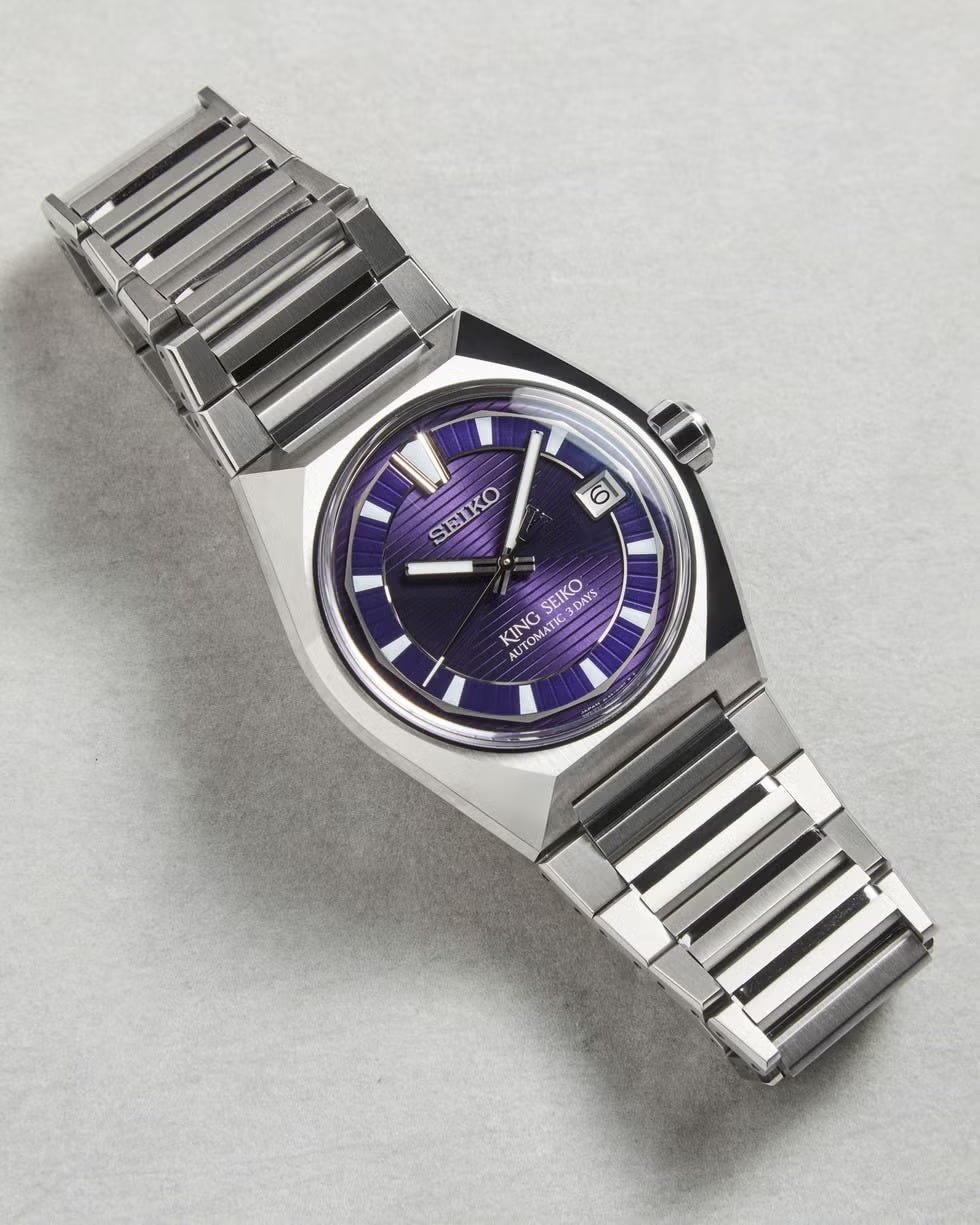 a stylish automatic wristwatch with a purple dial and stainless steel bracelet