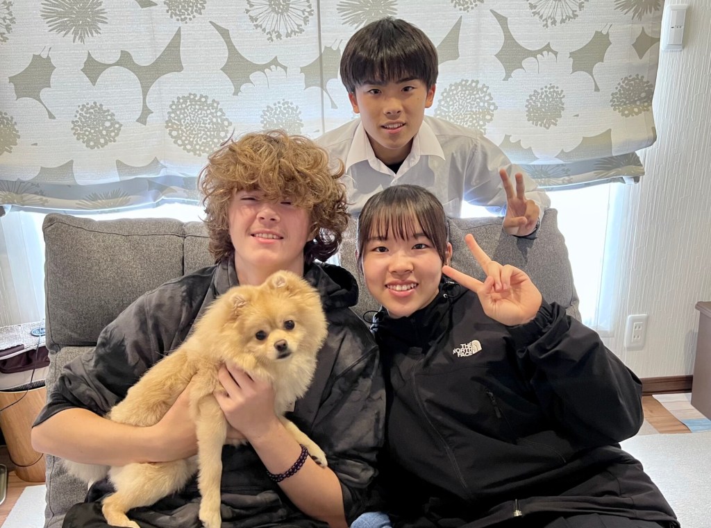 On the day of his departure from Mombetsu, Nick Crews (left), then a Newport High School sophmore, commemorated his sister cities visit with this portrait of members of his host family, the Watanabes: Aya (next to him), Tomo, and dog, Mugi. Crews, now a University of Oregon freshman, plans a second visit this year. Crews says the Japanese "are the nicest people I've ever met.” Photo courtesy: Nick Crews