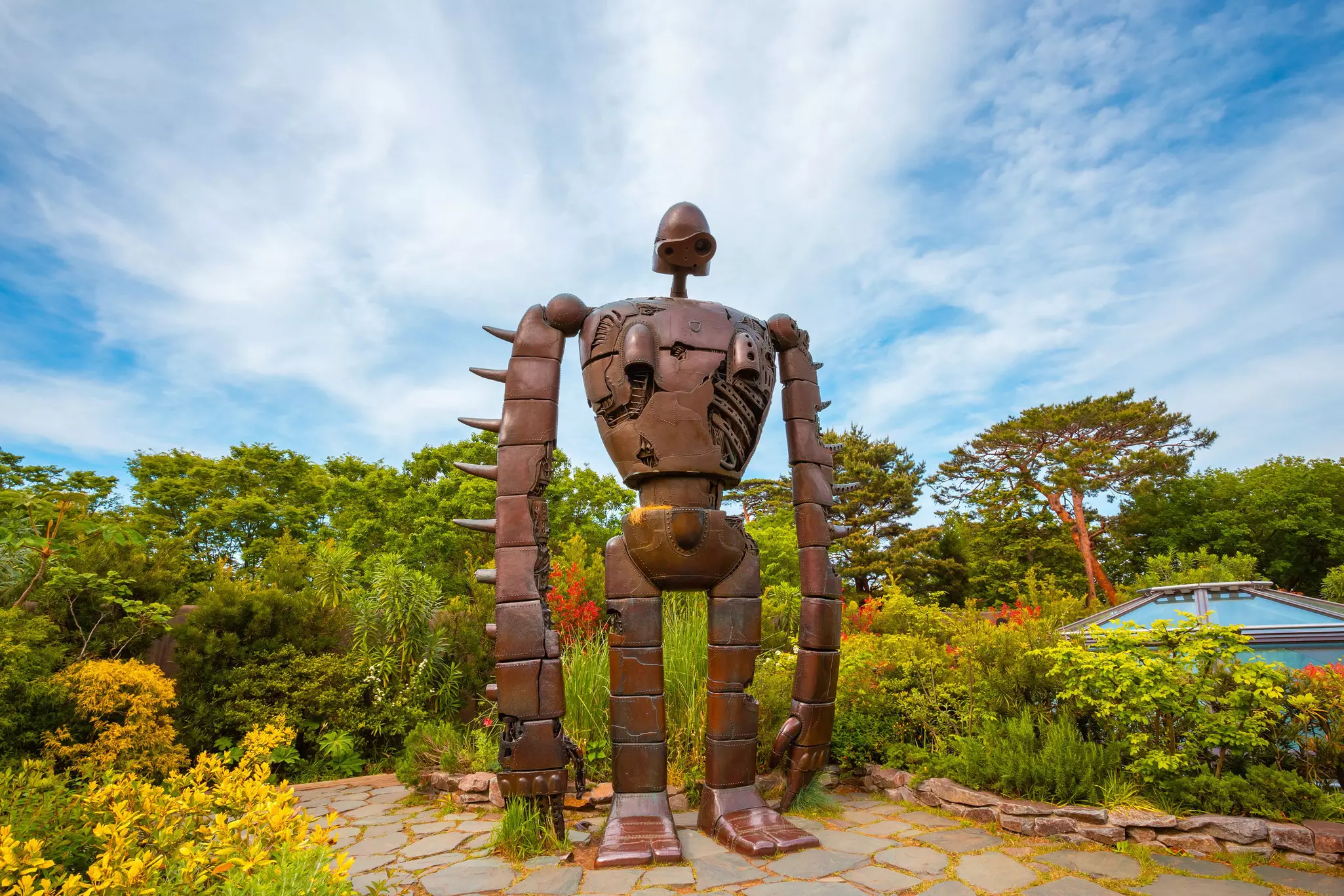 A metal robot statue in a flowering garden at a museum in Tokyo, Japan.