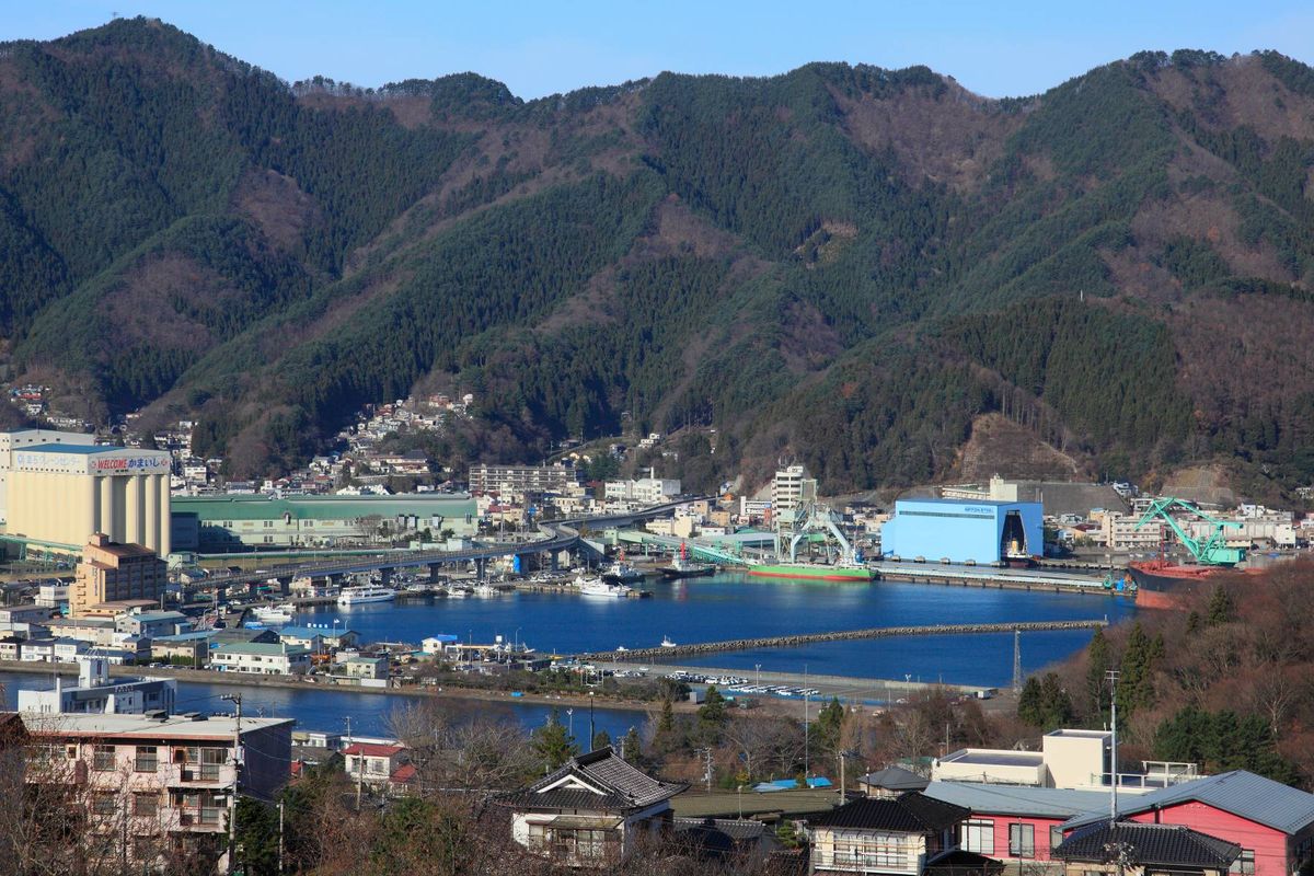 An aerial view of a town with a body of water and mountains in the background.