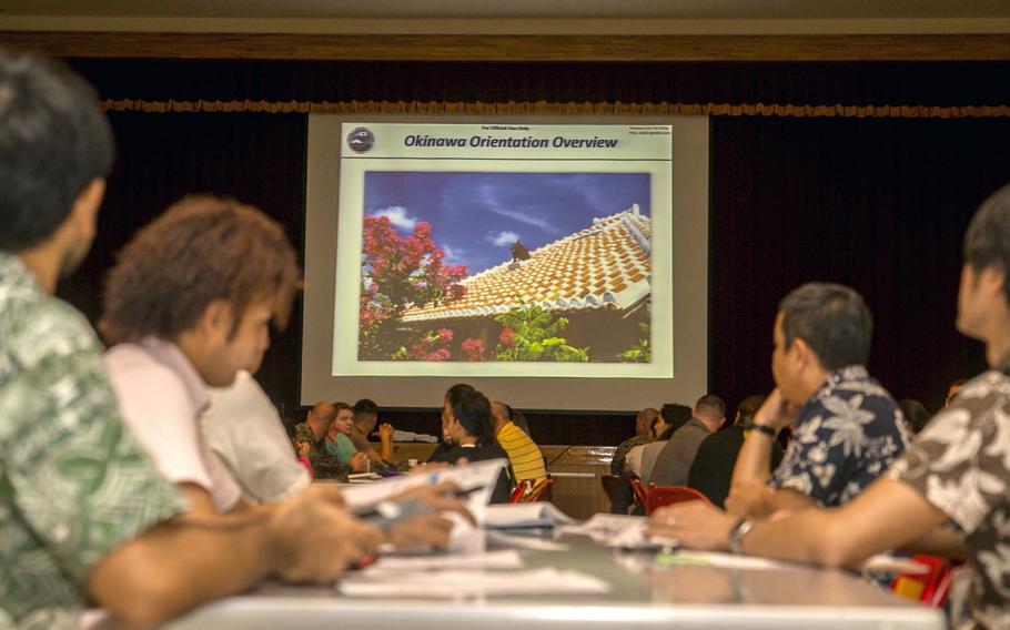 People sit at tables in front a projected presentation.
