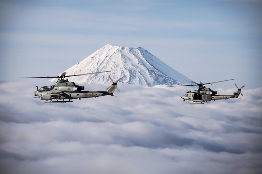 Mount Fuji Flyby | U.S. Department of War Two Marine Corps helicopters, an AH-1Z Viper and UH-1Y Venom, fly past Mount Fuji, Shizuoka, Japan, March 12, 2017. The helicopters are assigned to Marine Light Attack Helicopter Squadron 267, which is supporting Marine Aircraft Group 36, 1st Marine Aircraft Wing and 3rd Marine Expeditionary Force. The Marines validated the long-range capability of auxiliary fuel tanks on their H-1 platform helicopters by flying 314 nautical miles during one leg of the four-day mission. The extended range is crucial to maintaining a stronger, more capable forward-deployed force in the Indo-Asia-Pacific region. Marine Corps photo by Lance Cpl. Andy Martinez