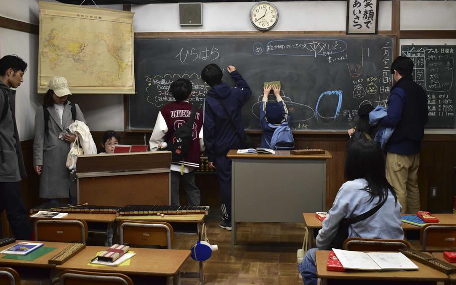 People explore a classroom setting in a museum.