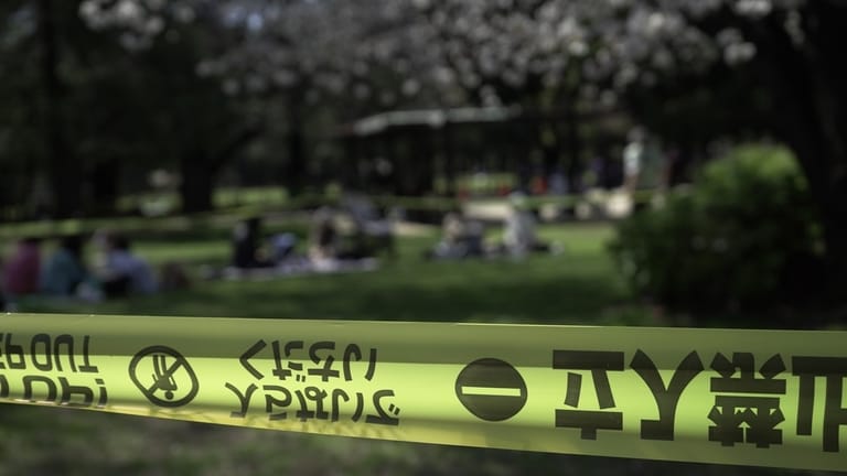 People sit down for a picnic outside a cordoned-off area...