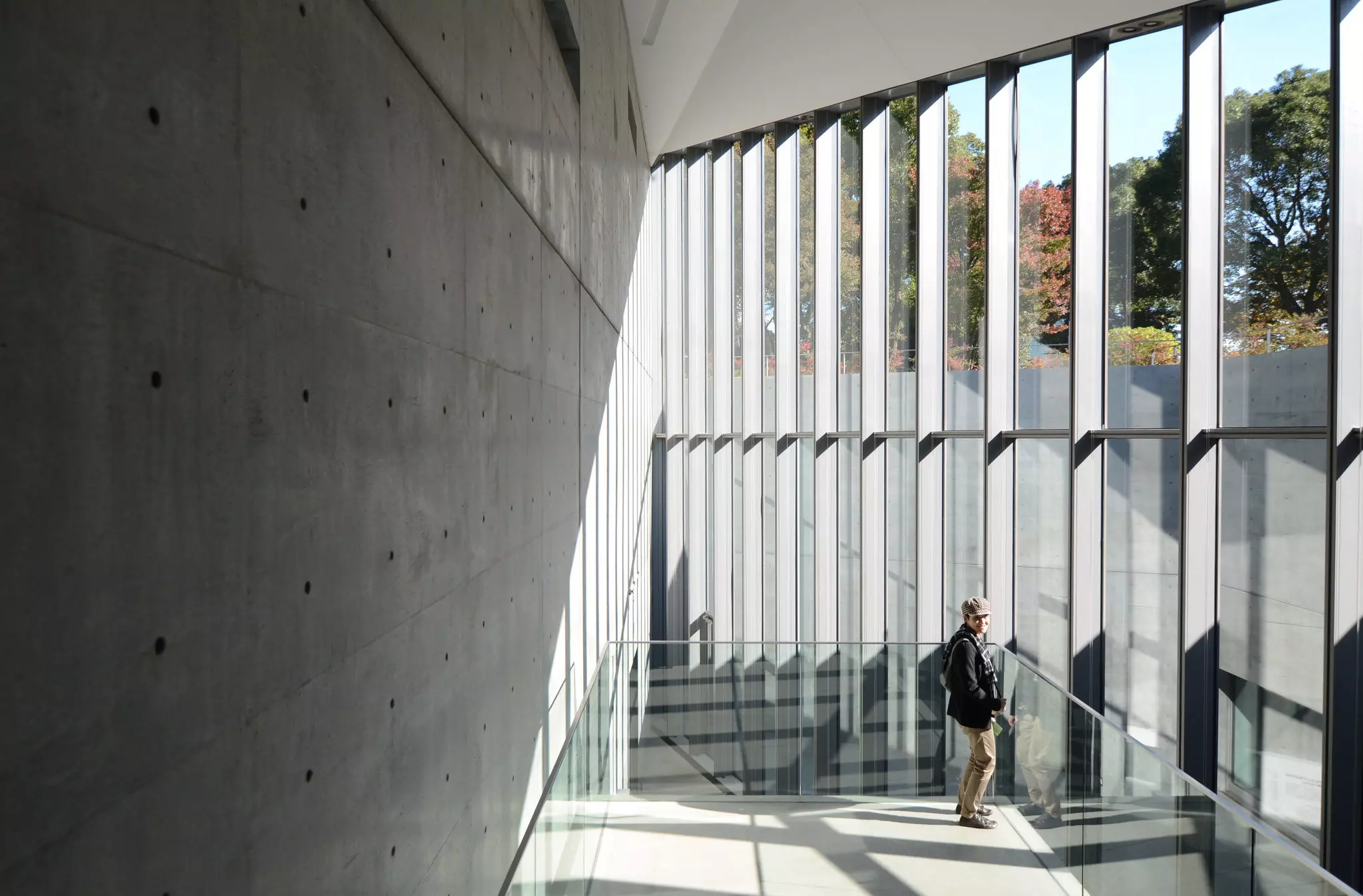 A man on a staircase with floor-to-ceiling windows inside a museum in Tokyo, Japan.