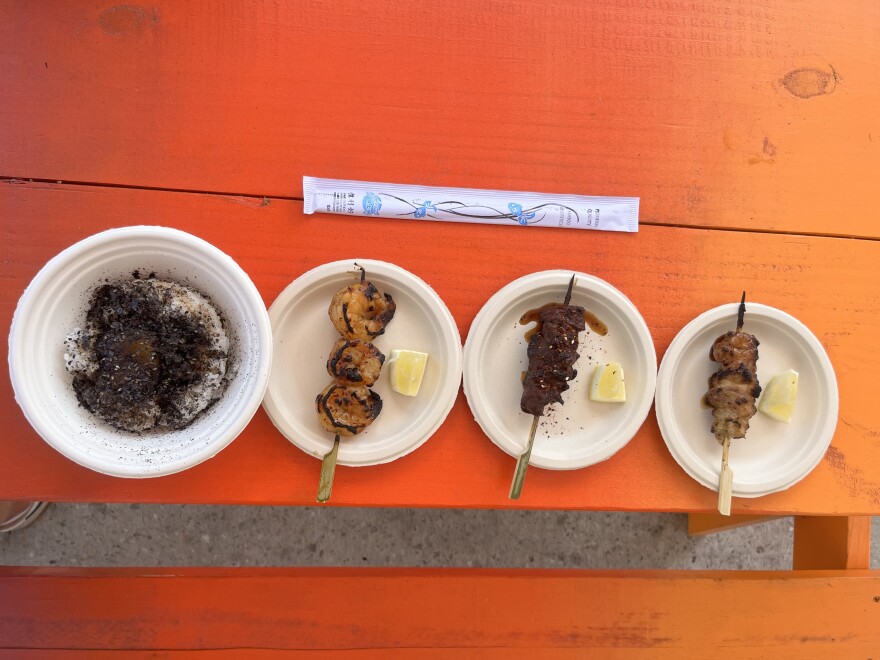 Dishes from Kushi & Co. in downtown Gainesville include Kushi rice with black truffle, tare and cured egg yolk (bottom), as well as shrimp, skirt steak and chicken thigh skewers flavored with an in-house tare and other marinades and seasonings. Picnic tables outside the restaurant were painted by artist Mr. Ganes. (Katie Klaiber, WUFT News)