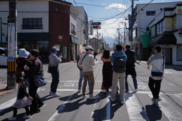 Foreign visitors stand to photograph Mount Fuji.